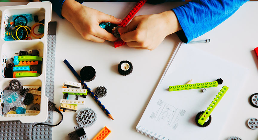 Hands using Lego bricks to build robotic vehicle