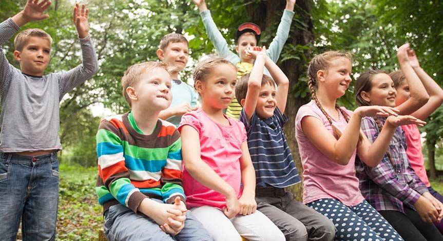 Group of positive children playing in the park sitting on the bench