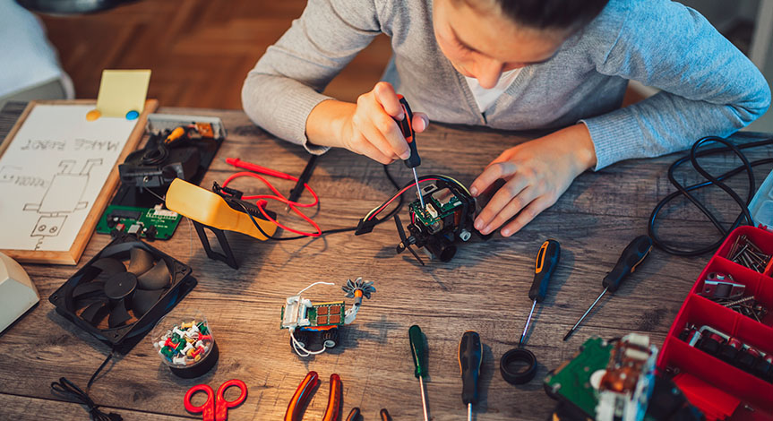 Girl constructs robotic toy. Robotic toy on a wood table full of tools
